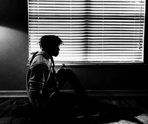 Side view of silhouette man sitting by window