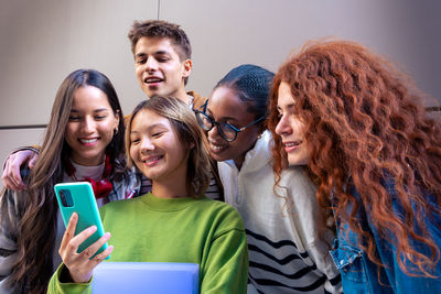 Portrait of smiling friends using mobile phone