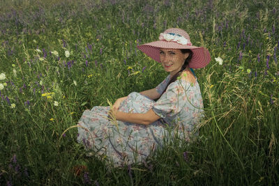 Rear view of woman wearing hat standing on grassy field