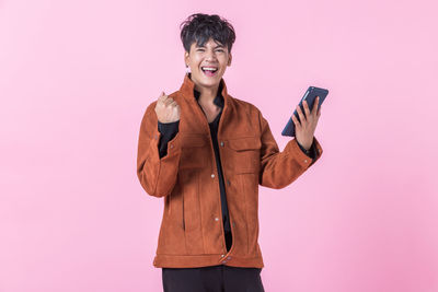 Portrait of smiling man standing against pink background