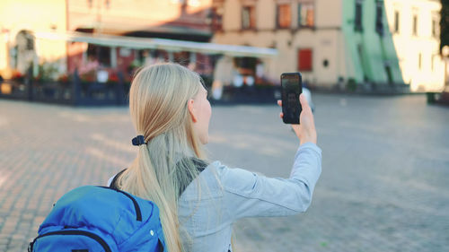 Midsection of woman photographing with mobile phone in city