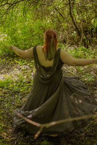 Rear view of woman standing in forest