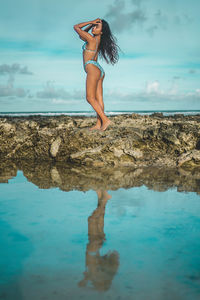 Woman standing in sea against sky