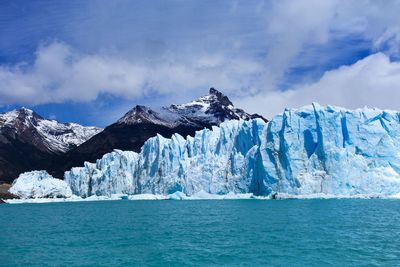 Scenic view of sea and snowcapped mountains against sky