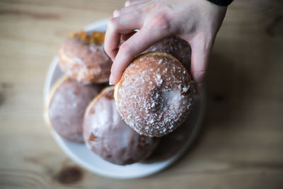 Cropped hand holding donut on table