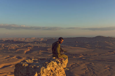 Man standing on rock against sky