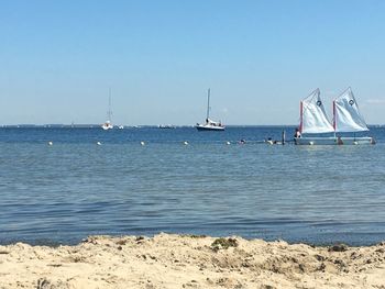 Sailboats on sea against clear sky