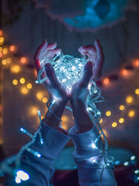 Close-up of woman holding illuminated christmas lights