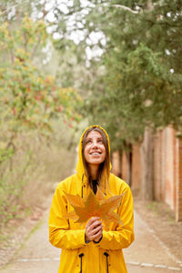 Woman holding autumn leaf on footpath