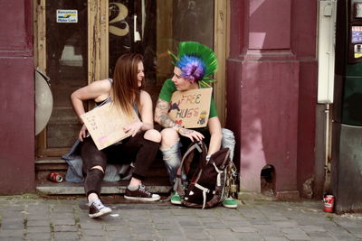 Full length of woman sitting in front of building