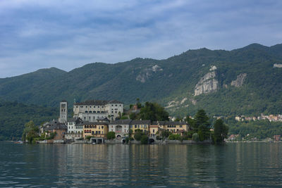 Buildings by river against mountain