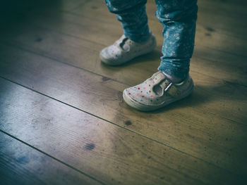 Low section of child standing on hardwood floor