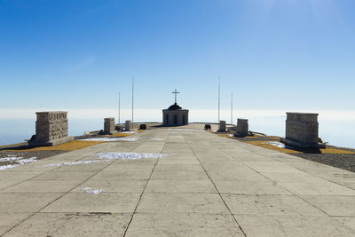 View of lighthouse by sea against clear blue sky