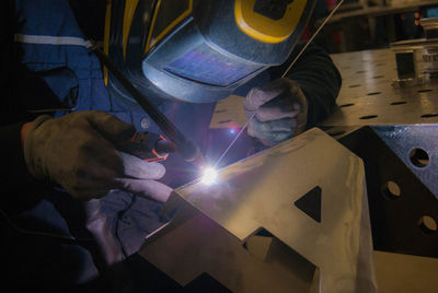 Close-up of man working on metal grate