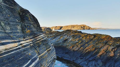 Rock formations in sea against clear sky