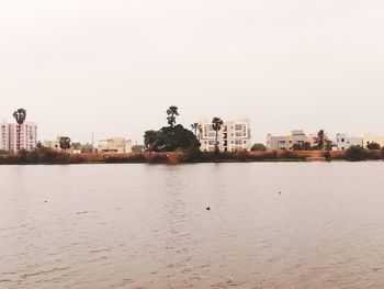 Scenic view of river by buildings against clear sky