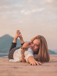 Portrait of woman relaxing at beach against sky