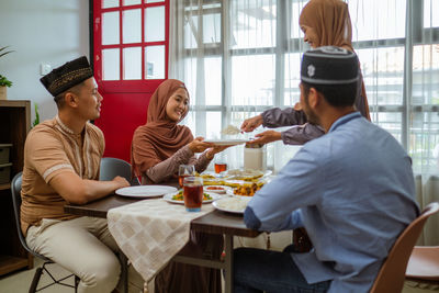 Smiling woman serving food to guests at home