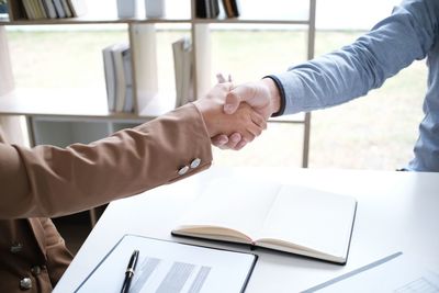 Cropped image of judge businesswoman shaking hands over desk