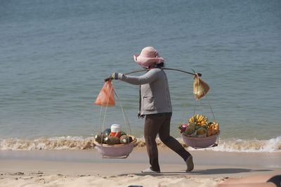 Rear view of woman with dog at beach