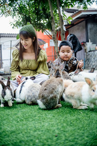 Easter bunny concept, mother and son are feeding carrots to easter bunny rabbit on grass, close up.