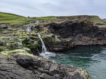 Scenic view of waterfall against sky