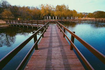 Footbridge over lake against sky