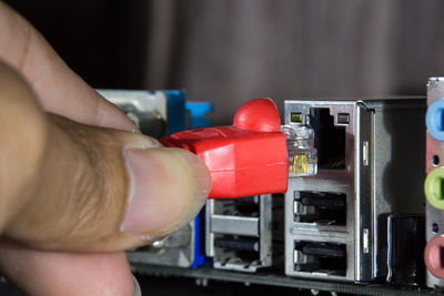 Cropped hand of person plugging usb cable in machine