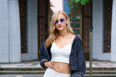 Young woman posing on the street of the city in a tracksuit and sunglasses