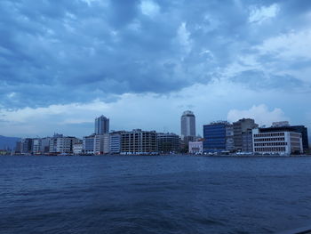 Sea by buildings against sky in city