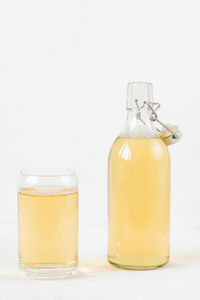 Home brewed kombucha fermented drink in glass and bottle on white. heathy homemade beverage