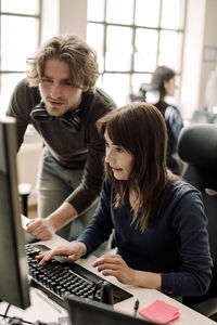 Male and female professionals discussing coding in office