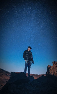 Full length of young man standing on rock against sky