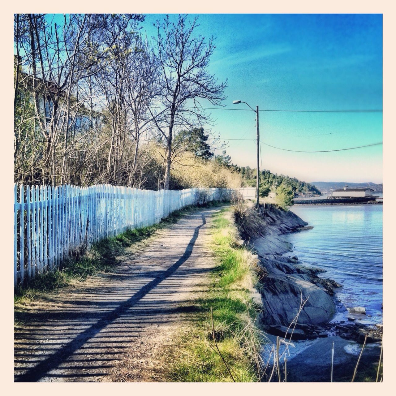 the way forward, diminishing perspective, blue, sky, water, transfer print, vanishing point, tranquil scene, tranquility, long, railing, tree, nature, scenics, beauty in nature, narrow, transportation, auto post production filter, sea, day