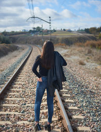 Rear view of woman walking on railroad track