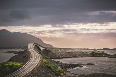 Scenic view of road amidst sea against sky during sunset