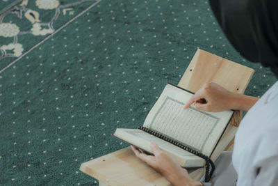 Midsection of woman reading koran