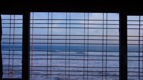 Full frame shot of swimming pool by sea against sky seen through window