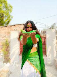 Portrait of young woman holding umbrella standing outdoors