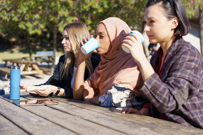 Young woman drinking beer while sitting on table