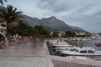 Crowd of tourists on promenade and moored boats in marina in touristic resort baska voda, croatia