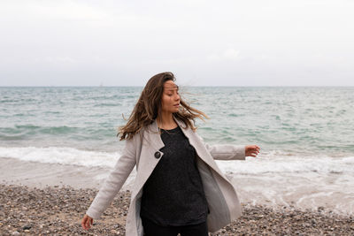 Woman standing on beach against sky