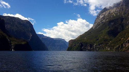 Scenic view of river by mountains against sky