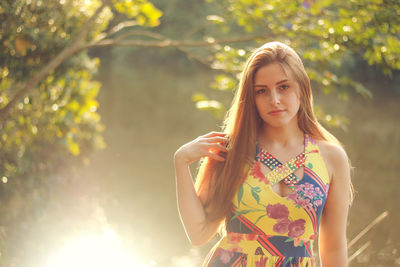 Portrait of smiling young woman standing against tree