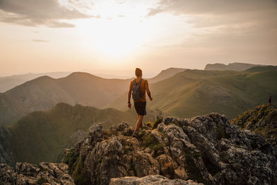 Rear view of man standing on rocks against mountain