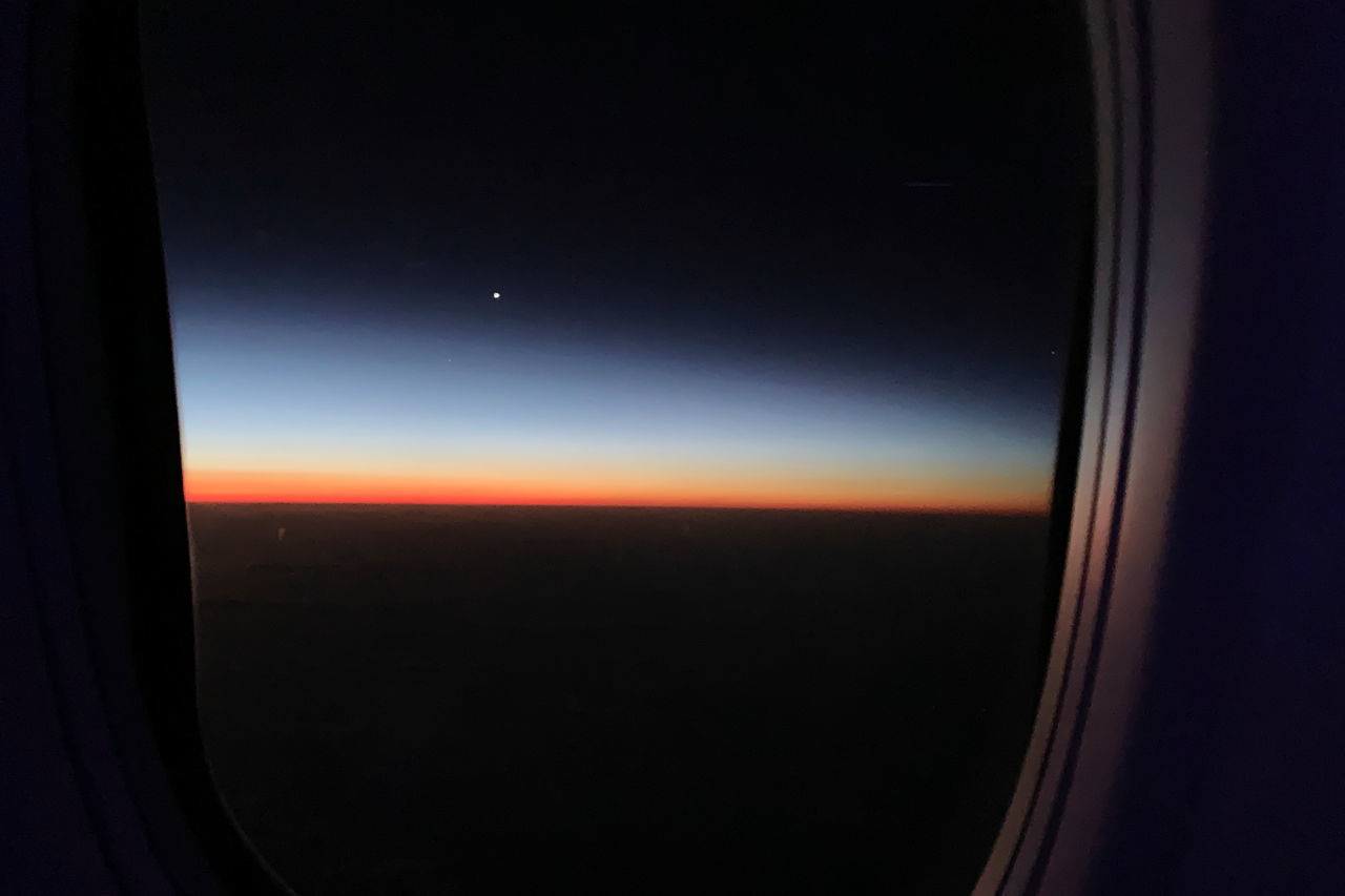 VIEW OF SKY THROUGH AIRPLANE WINDOW AT NIGHT