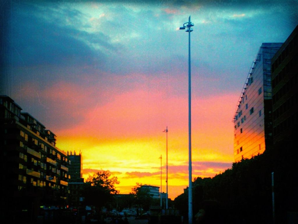 building exterior, sunset, architecture, sky, built structure, cloud - sky, city, silhouette, orange color, low angle view, street light, cloudy, cloud, residential structure, building, residential building, dusk, dramatic sky, house, outdoors