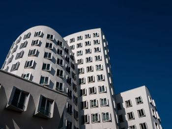 Low angle view of modern building against clear blue sky