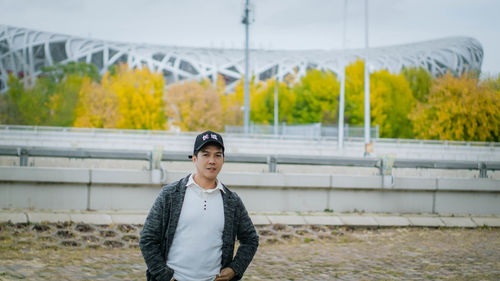 Portrait of young man standing against trees