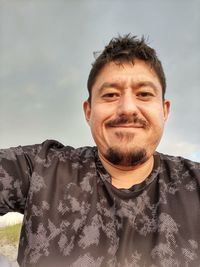Portrait of smiling man standing against sky